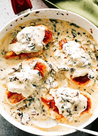 Four creamy Tuscan chicken breasts in a pan.