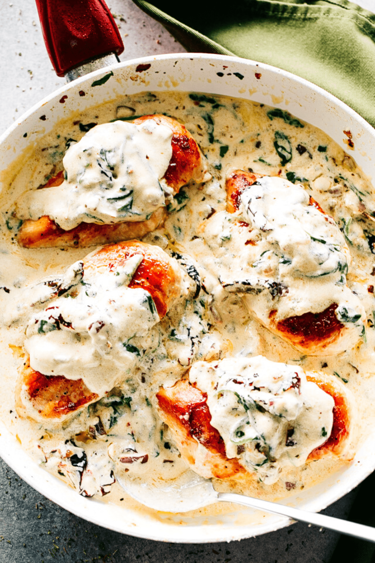 Four creamy Tuscan chicken breasts in a pan.