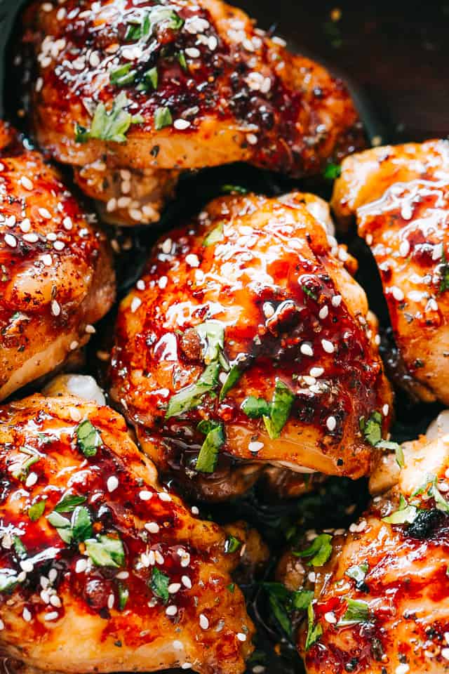 close up of Sticky Chicken Thighs topped with sesame seeds and parsley.