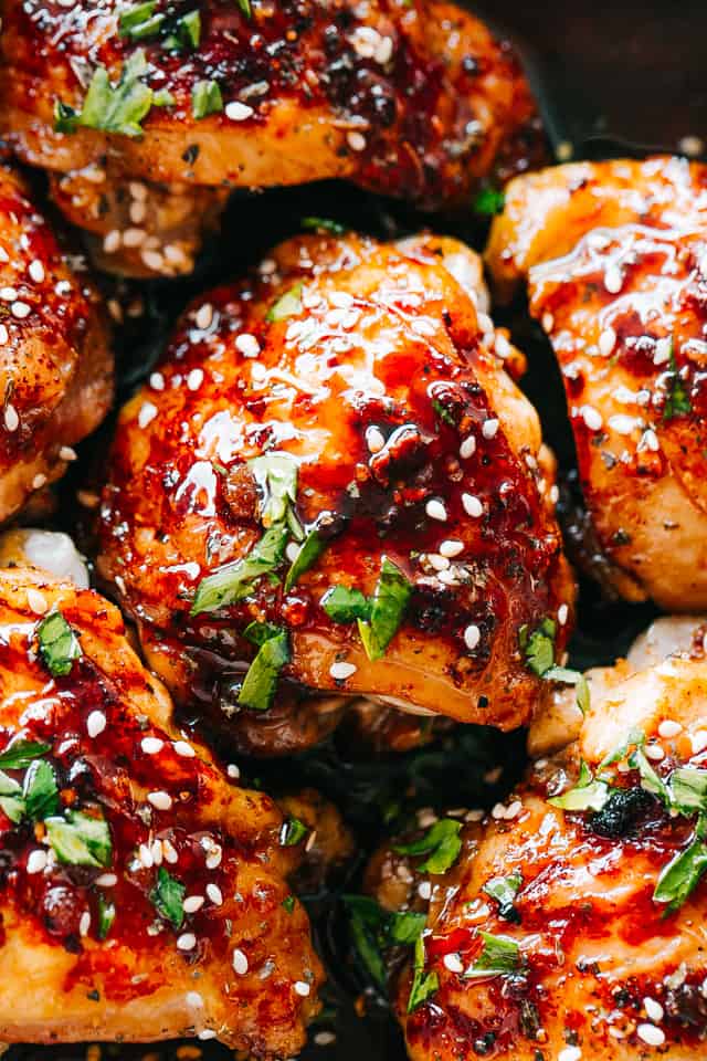 Close-up image of cooked chicken thighs topped with sesame seeds and chopped cilantro.