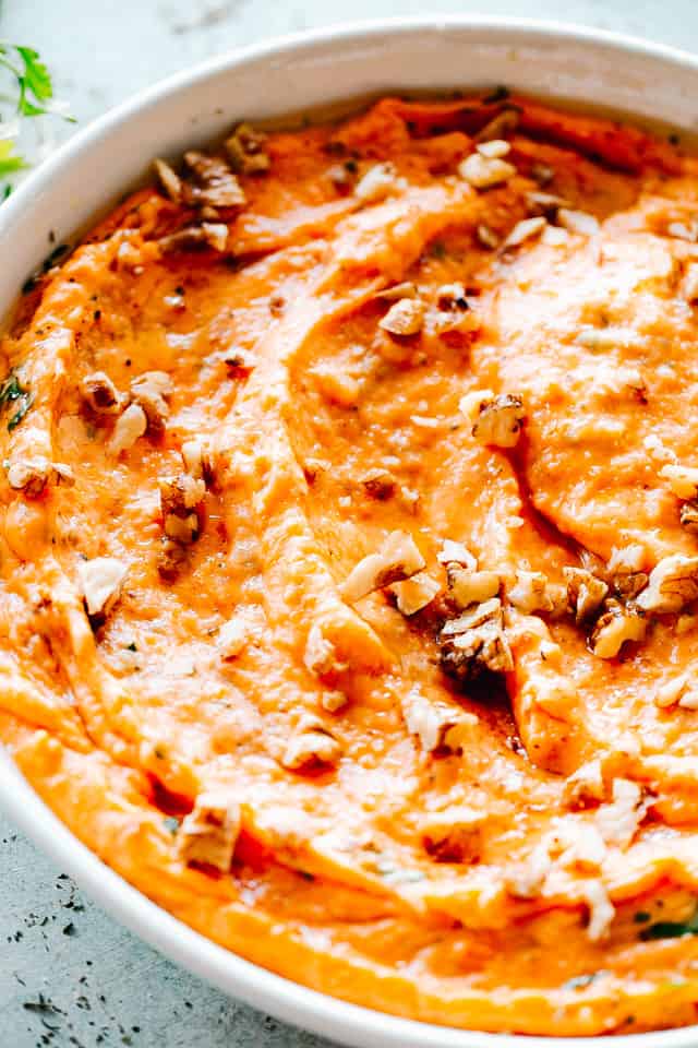Close-up image of Mashed Sweet Potatoes topped with chopped pecans.