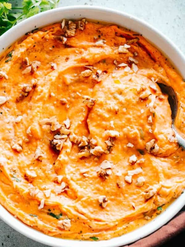 Mashed Sweet Potatoes served in a large white bowl with a spoon in the potato mash.