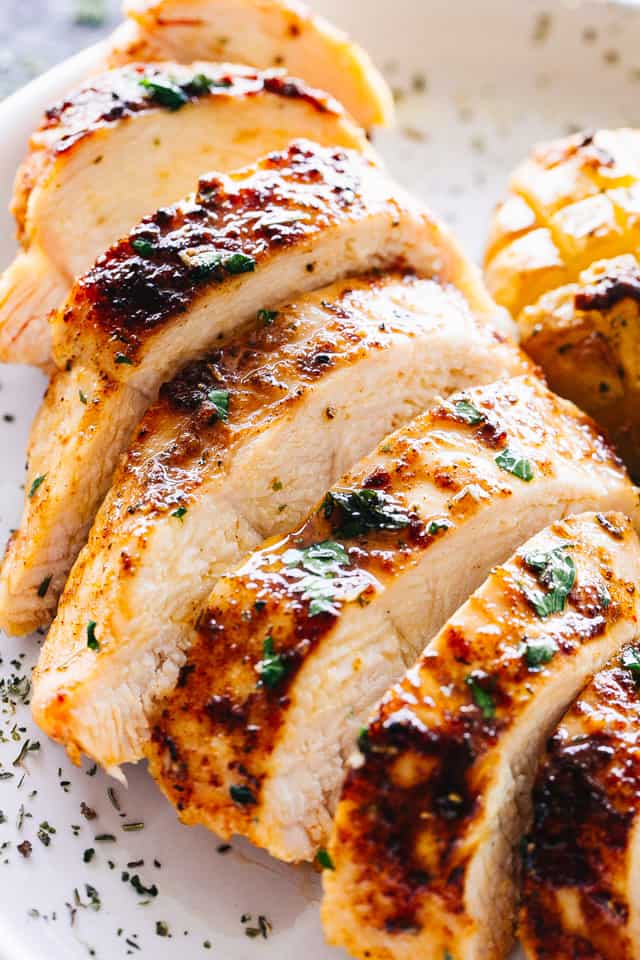 Sliced cooked chicken breasts on a white plate. 