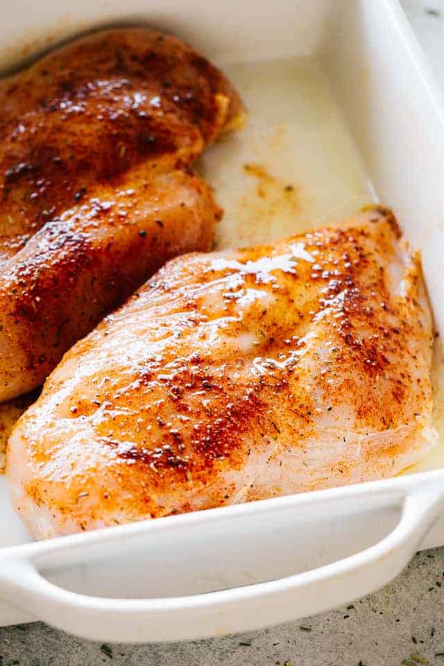 Raw seasoned chicken breasts in a baking dish.