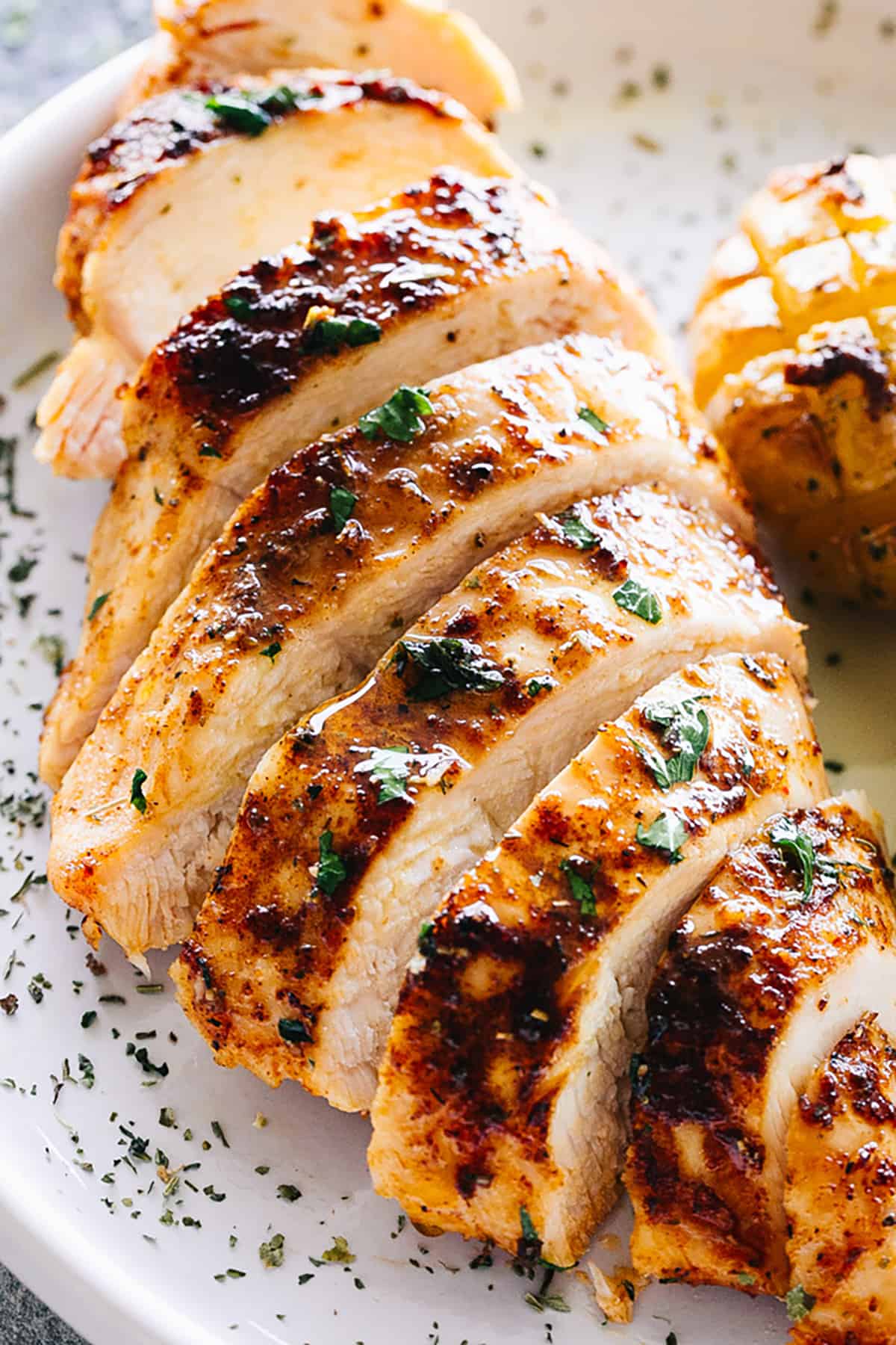 oven baked chicken breast cut into horizontal slices and set on a white dinner plate.