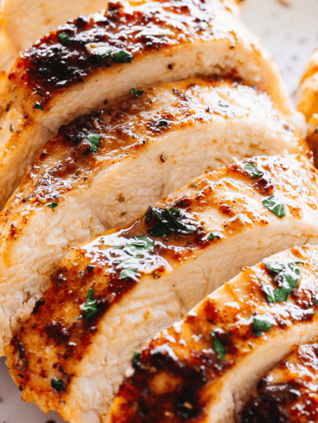 close up shot of juicy oven baked chicken breast cut into horizontal slices.