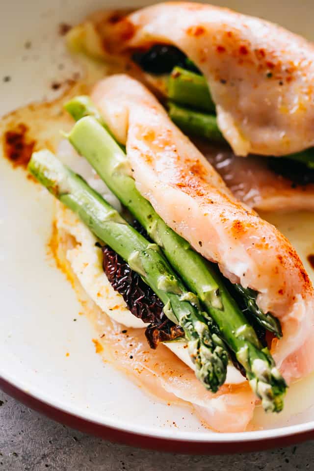 Raw chicken breasts stuffed with Asparagus and a slice of mozzarella cheese.
