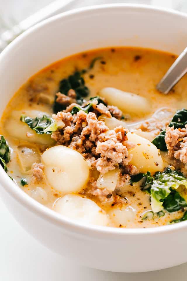 Close-up photo of Zuppa Toscana served in a bowl, with chunks of Italian sausage and gnocchi served in a creamy broth.