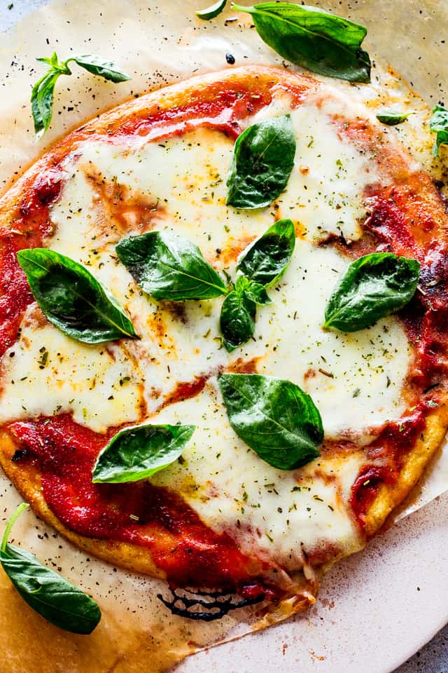 A homemade pizza with fresh basil leaves.