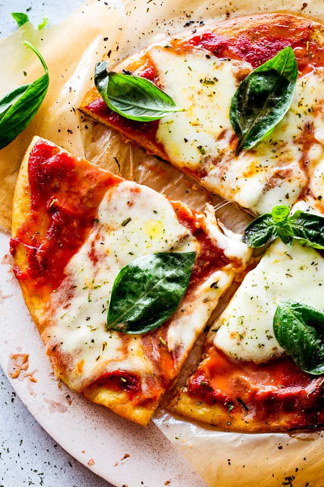 Sliced Keto Pizza topped with fresh basil leaves.