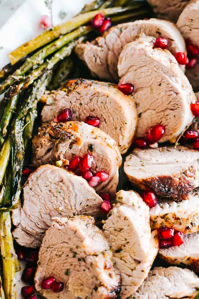 Pieces of roasted pork with roasted asparagus and pomegranate seeds on top