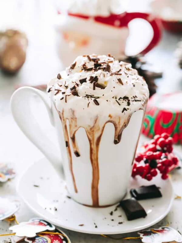 A cup of crock pot hot chocolate with whipped cream and chocolate shavings on top.