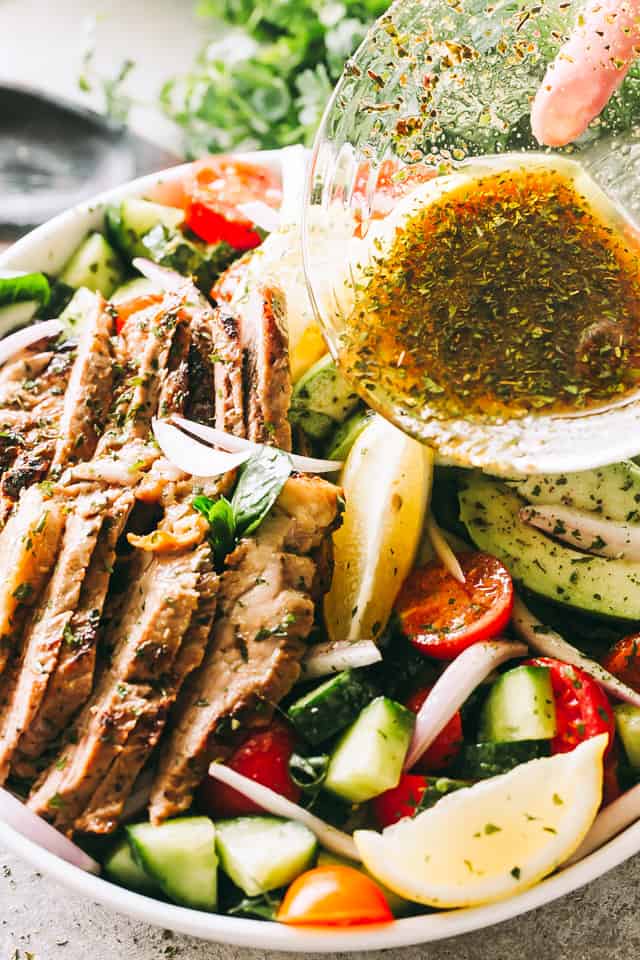 pouring balsamic dijon dressing over a Steak Salad.