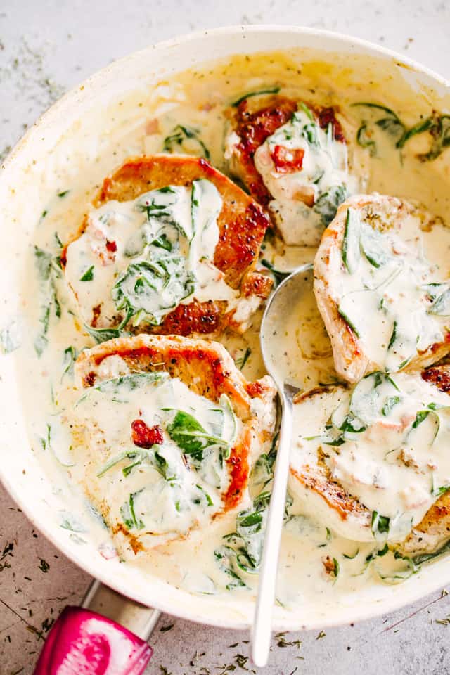 Overhead view of mustard pork chops in a skillet covered with creamy Dijon sauce.