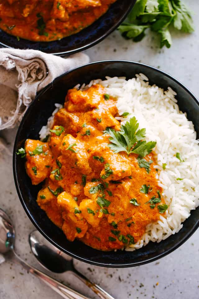 Instant Pot Butter Chicken served over rice in a black bowl.