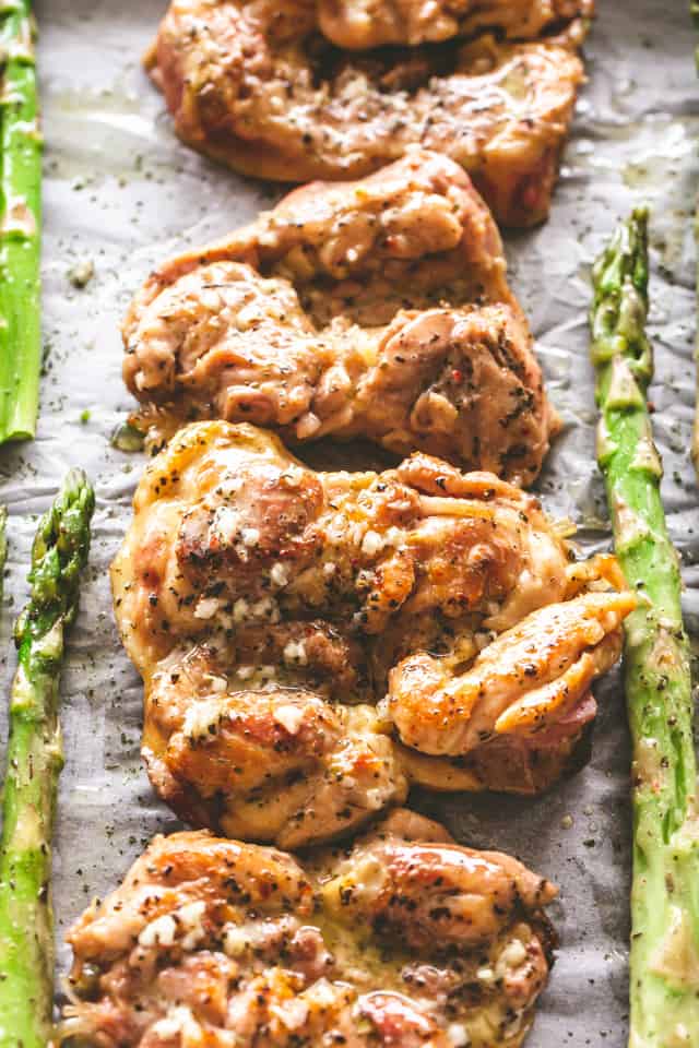 Lemon garlic chicken thighs arranged in a row on a sheet pan.