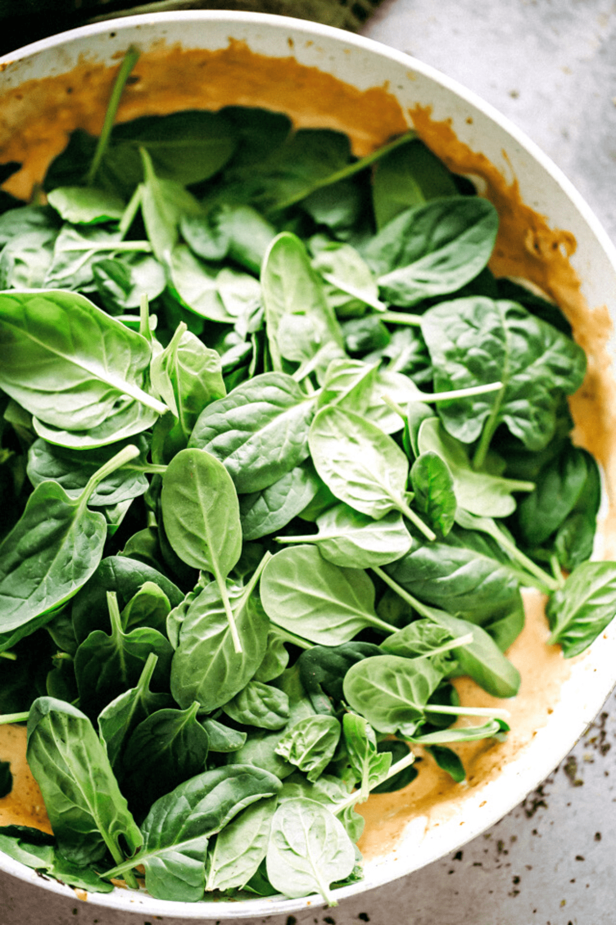 cooking down spinach leaves in a skillet with heavy cream.