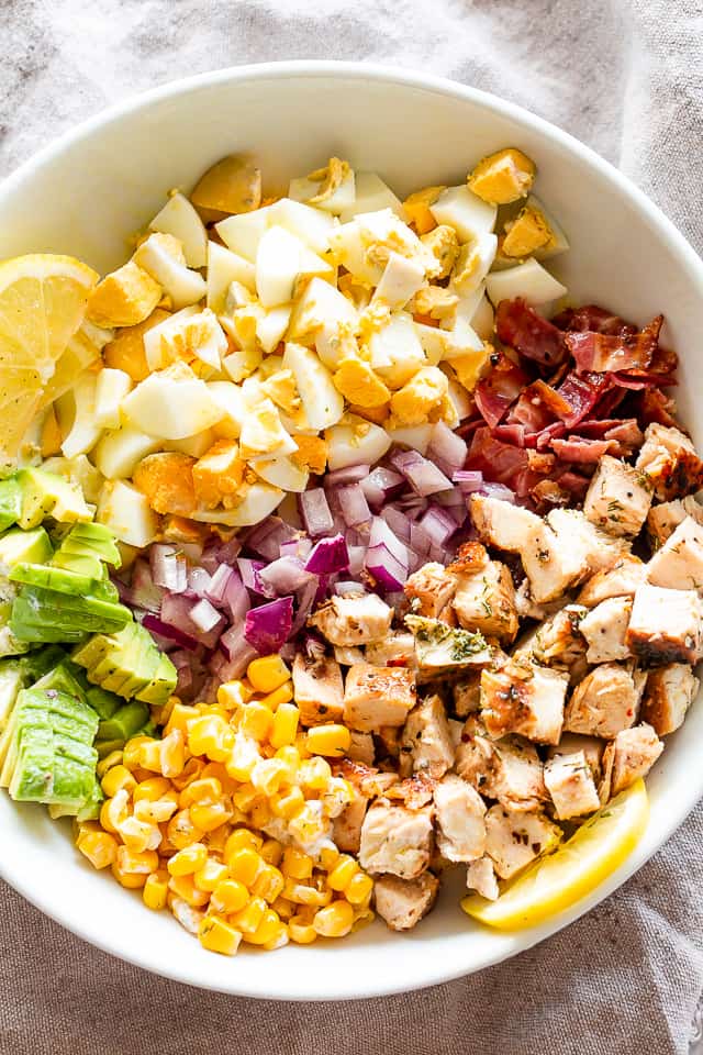 Chopped Eggs, avocados, bacon, chicken, red onions, and corn in a Salad bowl