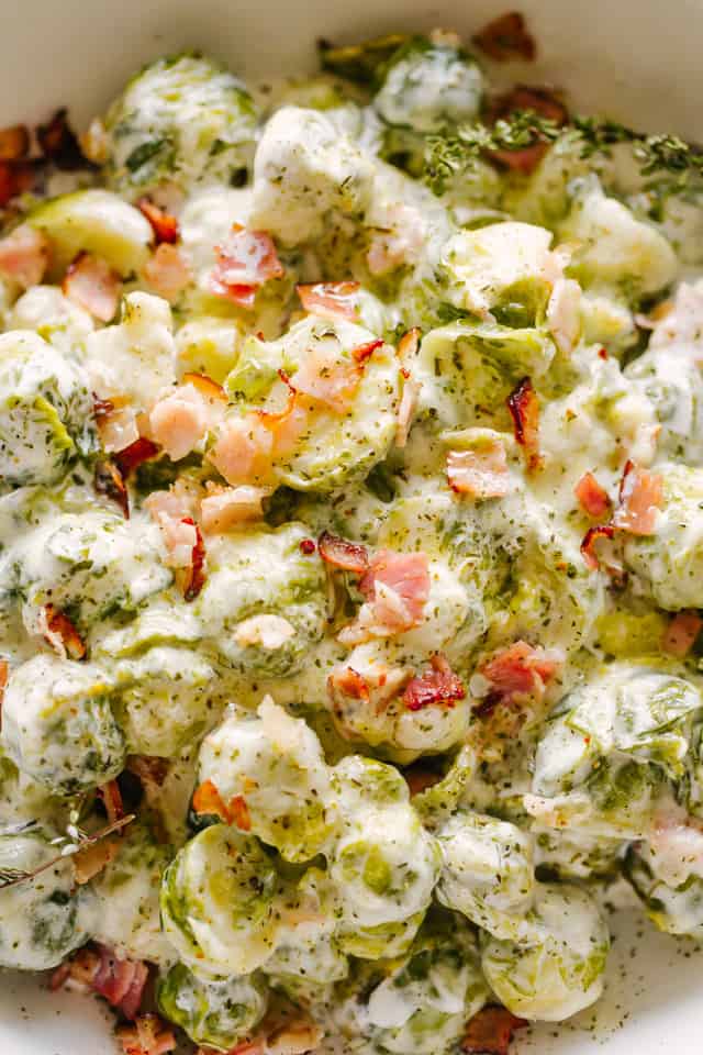 Make creamy Brussels sprouts in the Instant Pot in minutes, smothered in cheese sauce with bacon. An easy low-carb, keto-friendly side dish! Overhead view of careamy instant pot Brussels sprouts with bacon in a serving bowl.