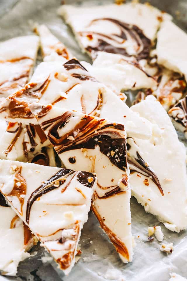 Chocolate peanut butter frozen yogurt bark broken up on a sheet of parchment paper.