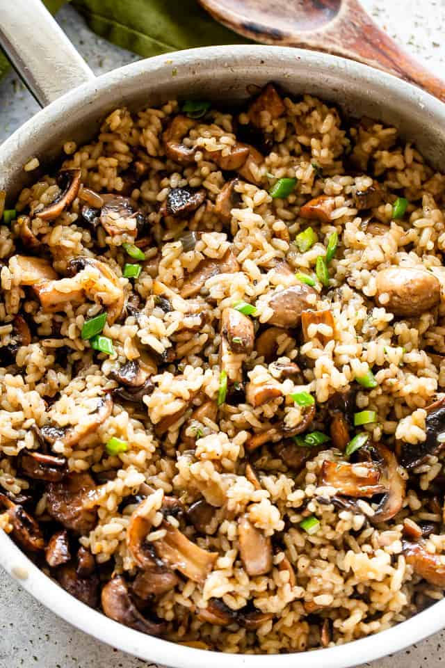 Overhead view of a pot of mushroom rice garnished with green onions. 