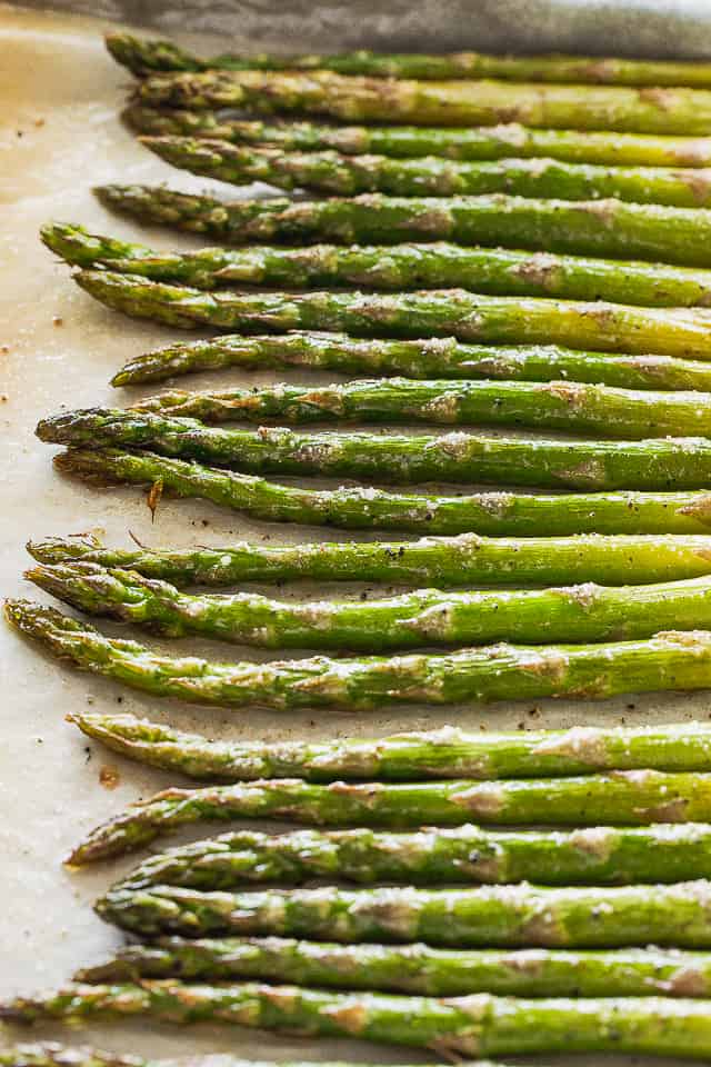 Cooked asparagus on parchment paper covered in hollandaise sauce