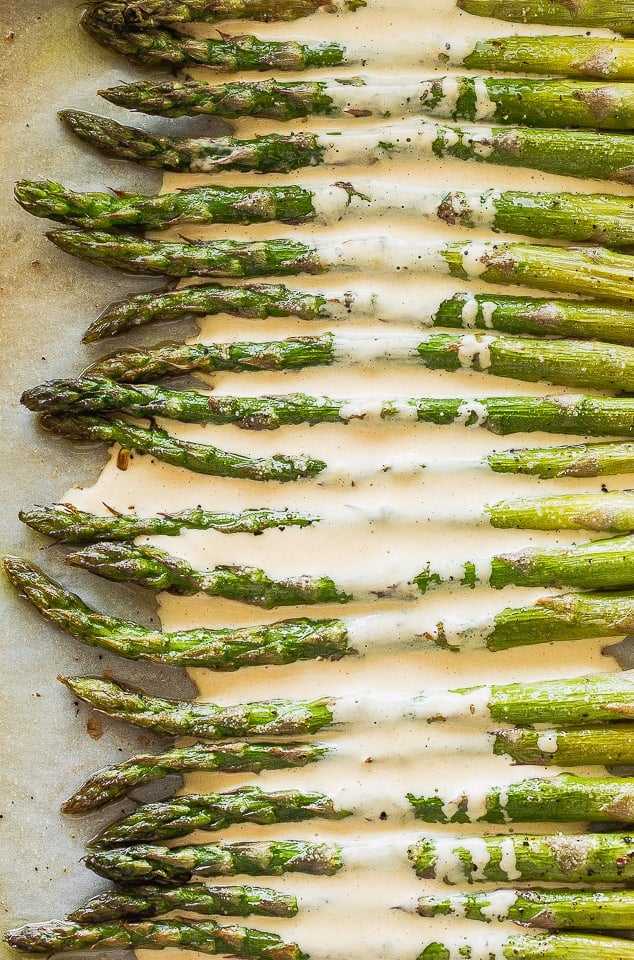 Cooked asparagus on parchment paper covered in hollandaise sauce