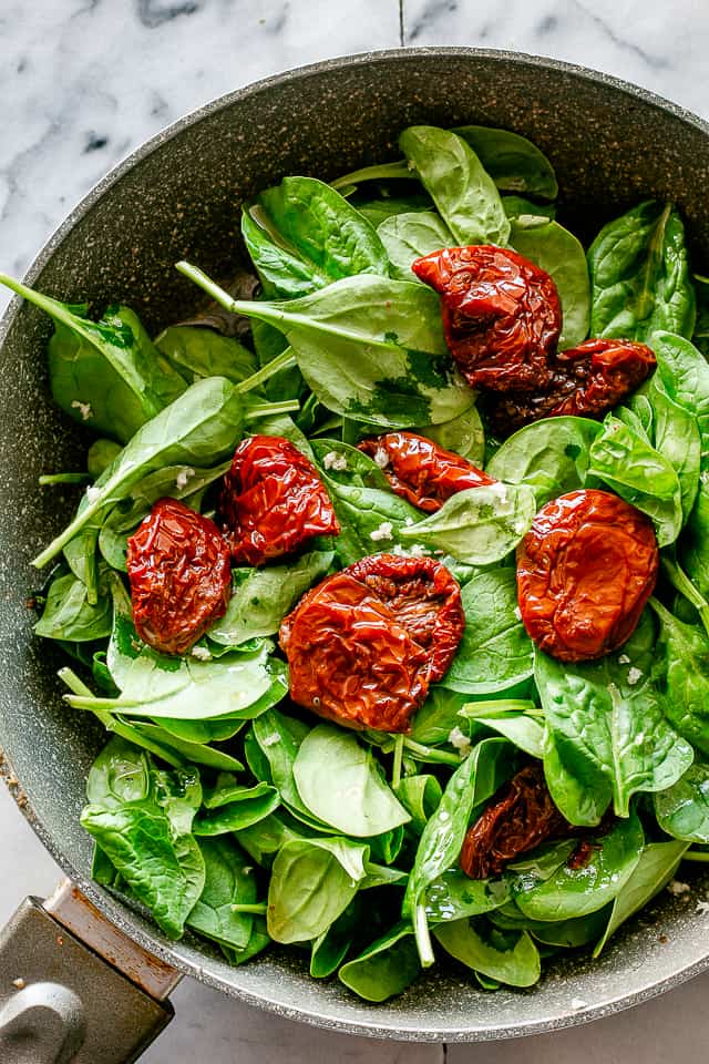 Baby spinach and sun-dried tomatoes in a skillet.