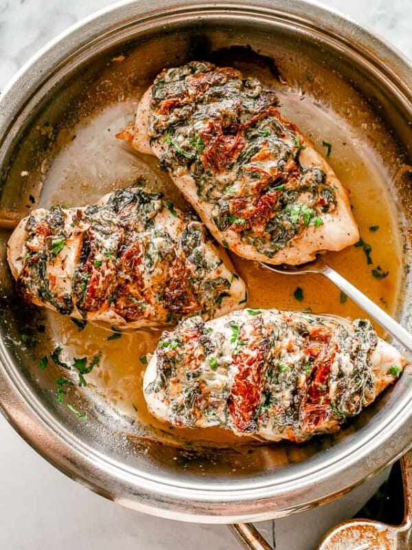 Hasselback chicken breasts in a skillet.