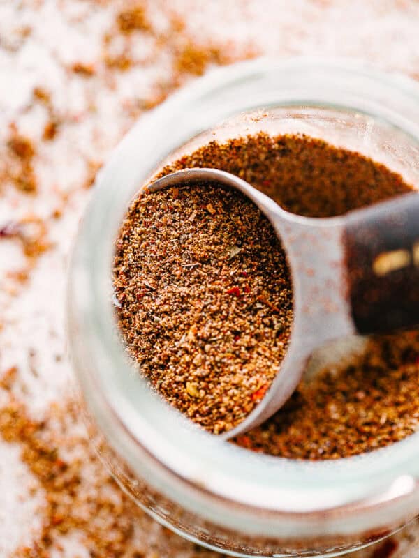 A spoon scooping Homemade Taco Seasoning out of a mason jar.