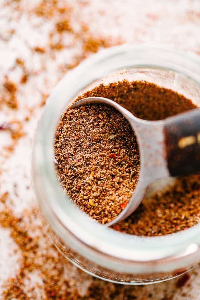 A spoon scooping Homemade Taco Seasoning out of a mason jar.