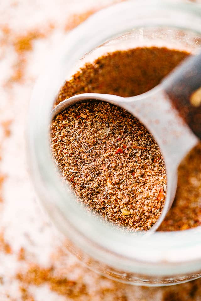 A spoon scooping Homemade Taco Seasoning out of a mason jar.