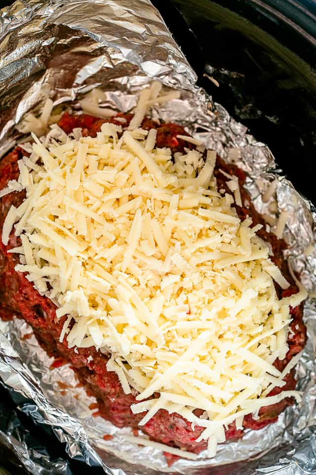 Meatloaf in a slow cooker topped with cheese.