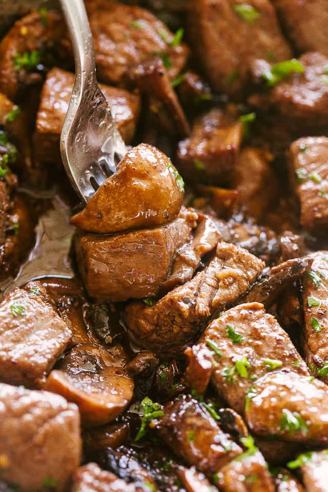 Mushrooms and steak bites on a fork.