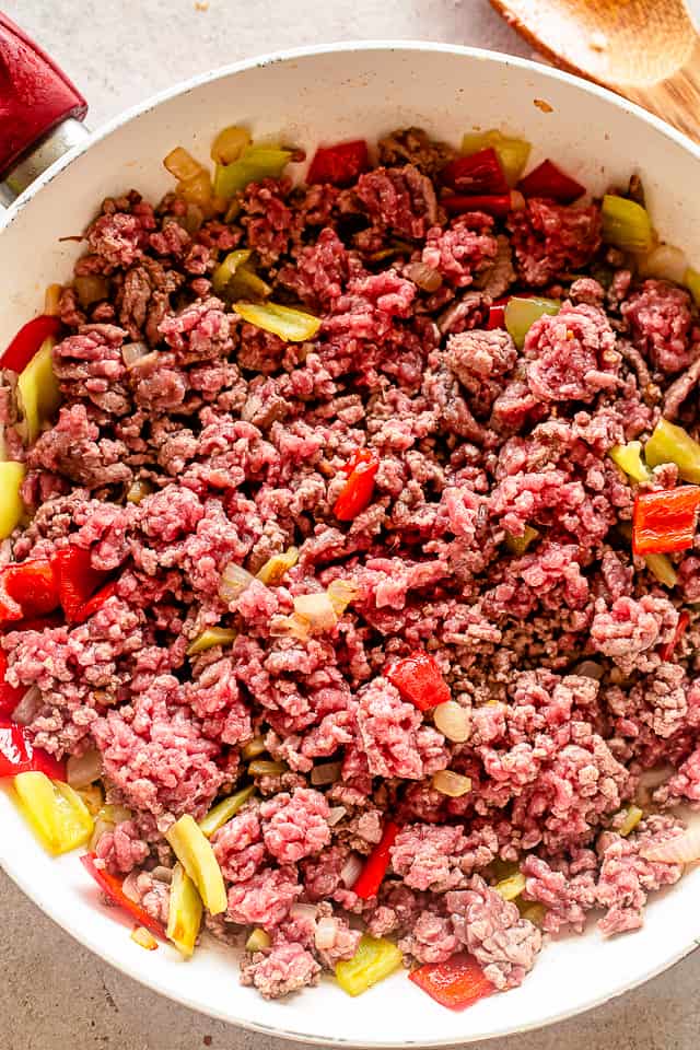 Raw ground beef cooking in a skillet.