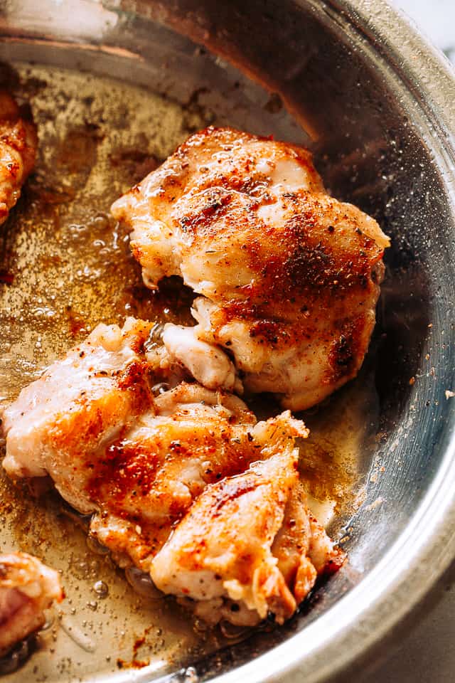 Browning chicken thighs in a skillet.
