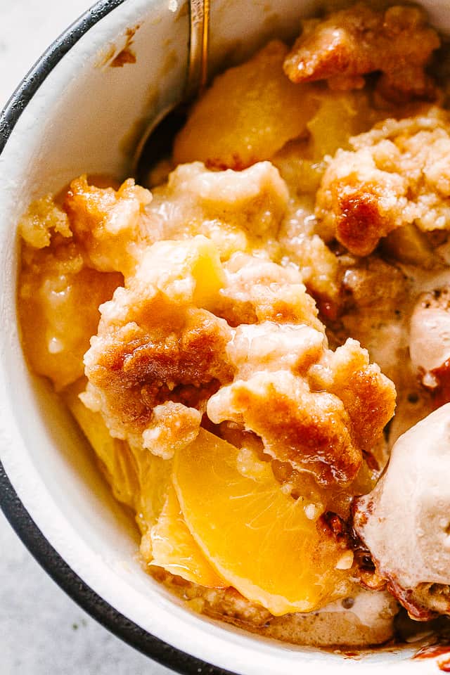 Peach Cobbler served in a bowl with ice cream.