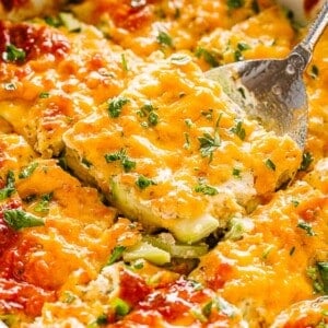 Lifting up a slice of zucchini casserole from a baking dish.