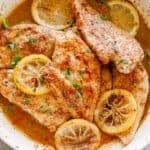 Lemon pepper chicken breasts in a skillet.