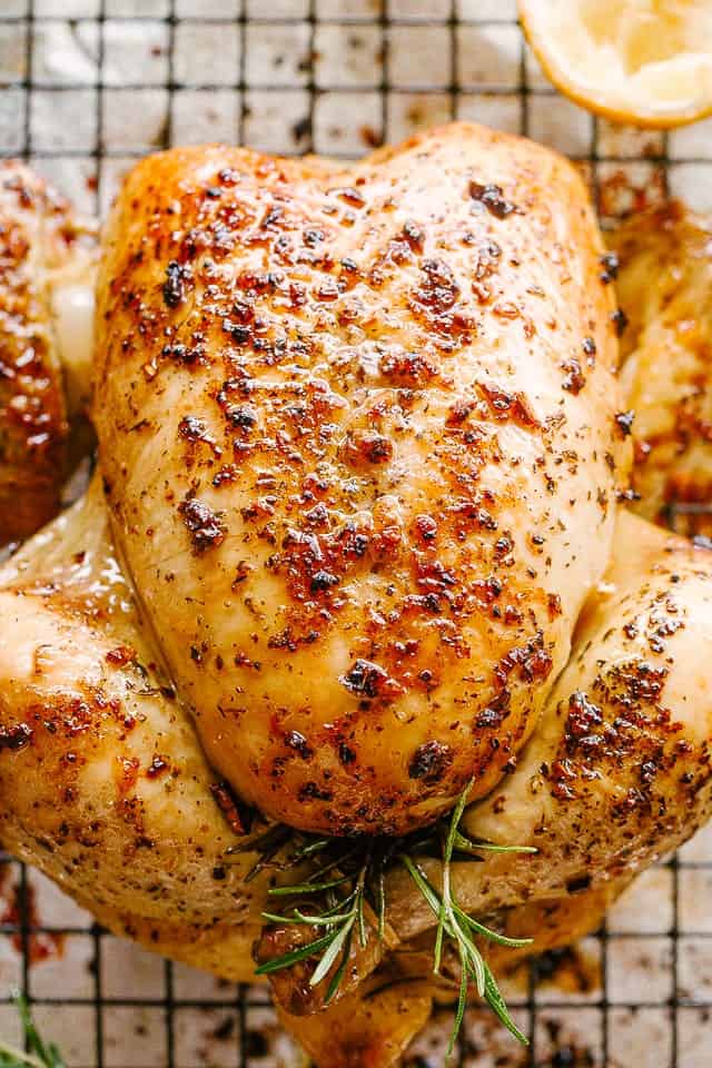 Roast Chicken on a rack next to half a lemon and rosemary sprigs.