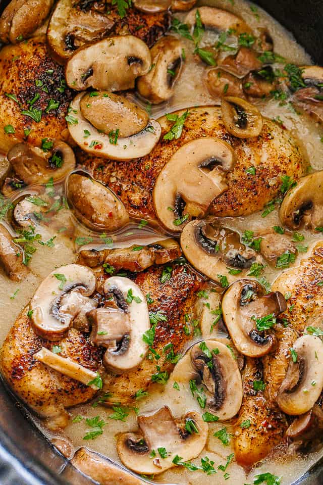 Cooked chicken cutlets topped with mushrooms in the crock pot
