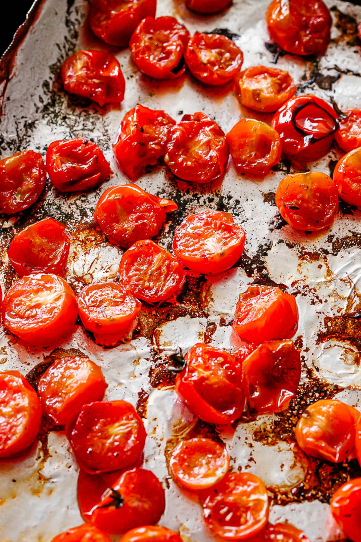 Roasted cherry tomatoes scattered on a baking sheet.