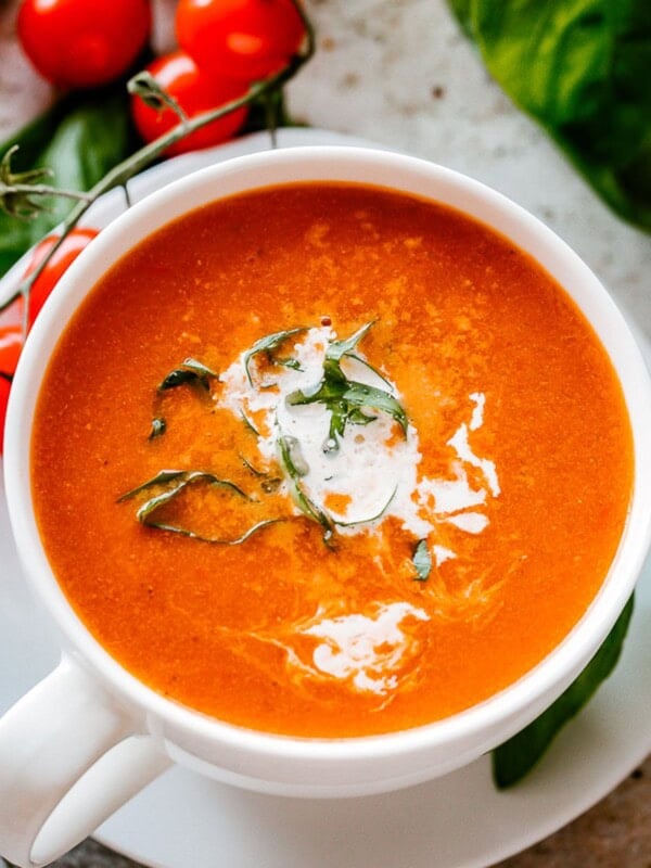 Bowl of Roasted Tomato Soup garnished with basil and parmesan cheese.