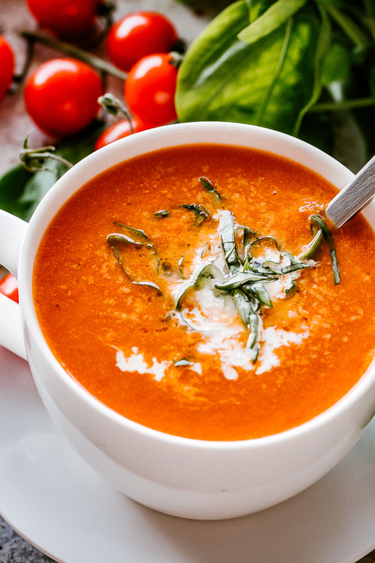 Roasted Tomato Soup in a mug with a spoon inside the soup.