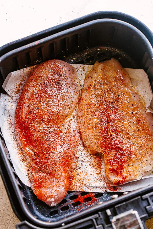Raw chicken breasts in an air fryer.