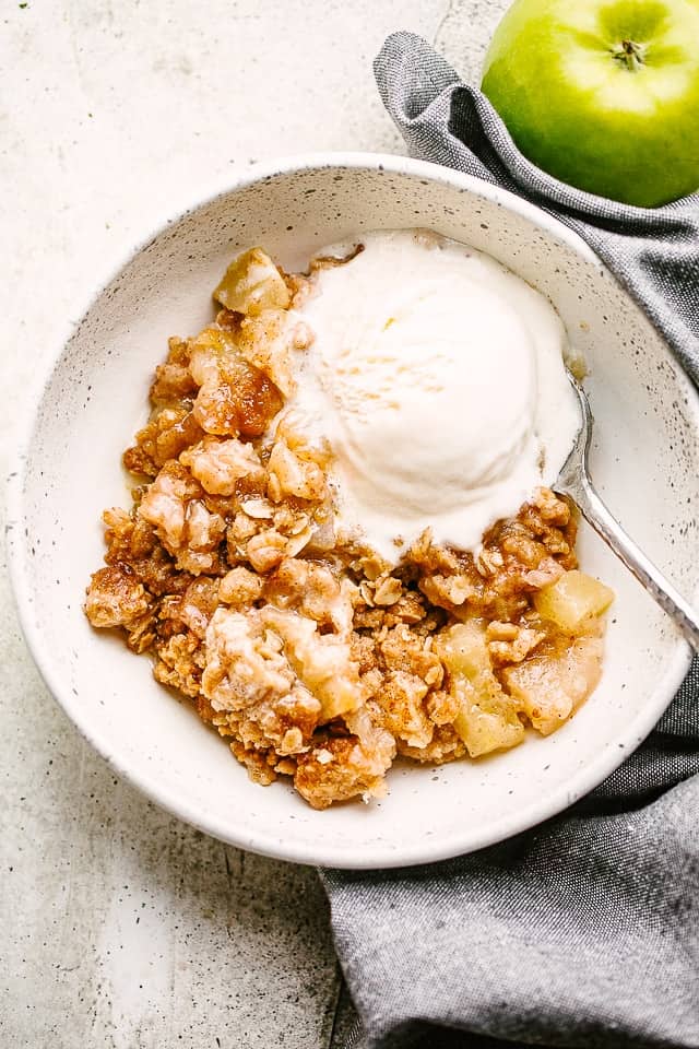 Apple Crumble served in a bowl with vanilla ice cream.