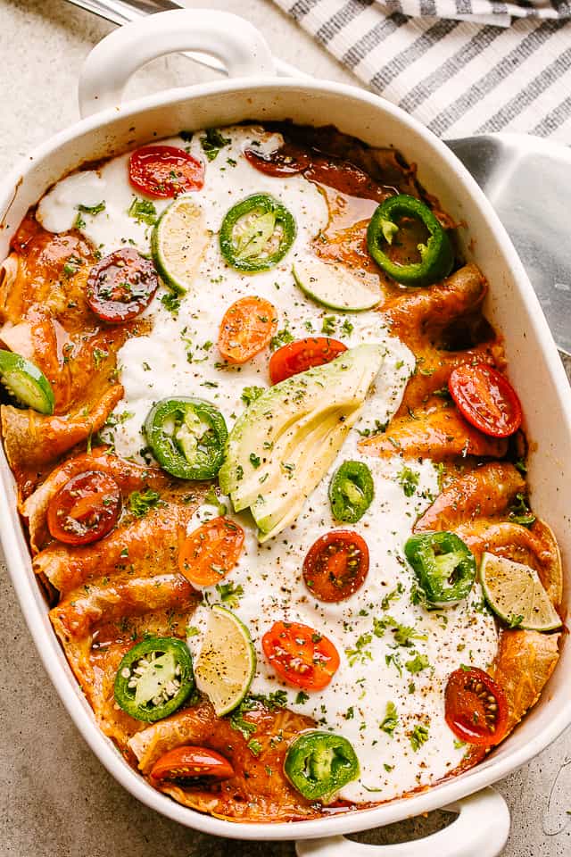 Baked Chicken Enchiladas topped with sour cream, jalapenos, and tomatoes.