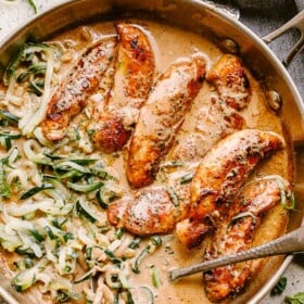Chicken tenders cooked in a skillet with cream sauce and zoodles.