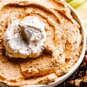Pumpkin Fluff Dip served in a bowl with a dollop of whipped topping.