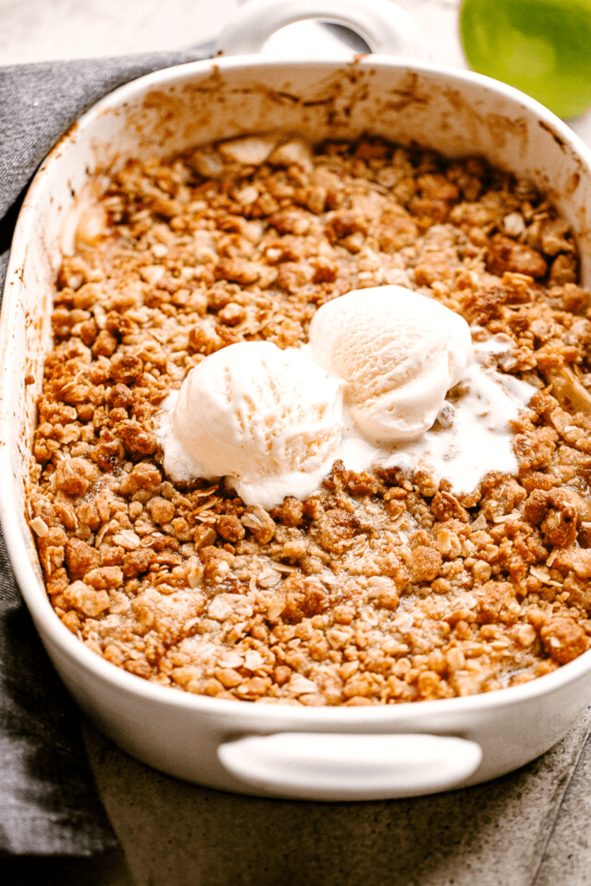 Baked Apple Crumble in a baking dish, and topped with vanilla ice cream.